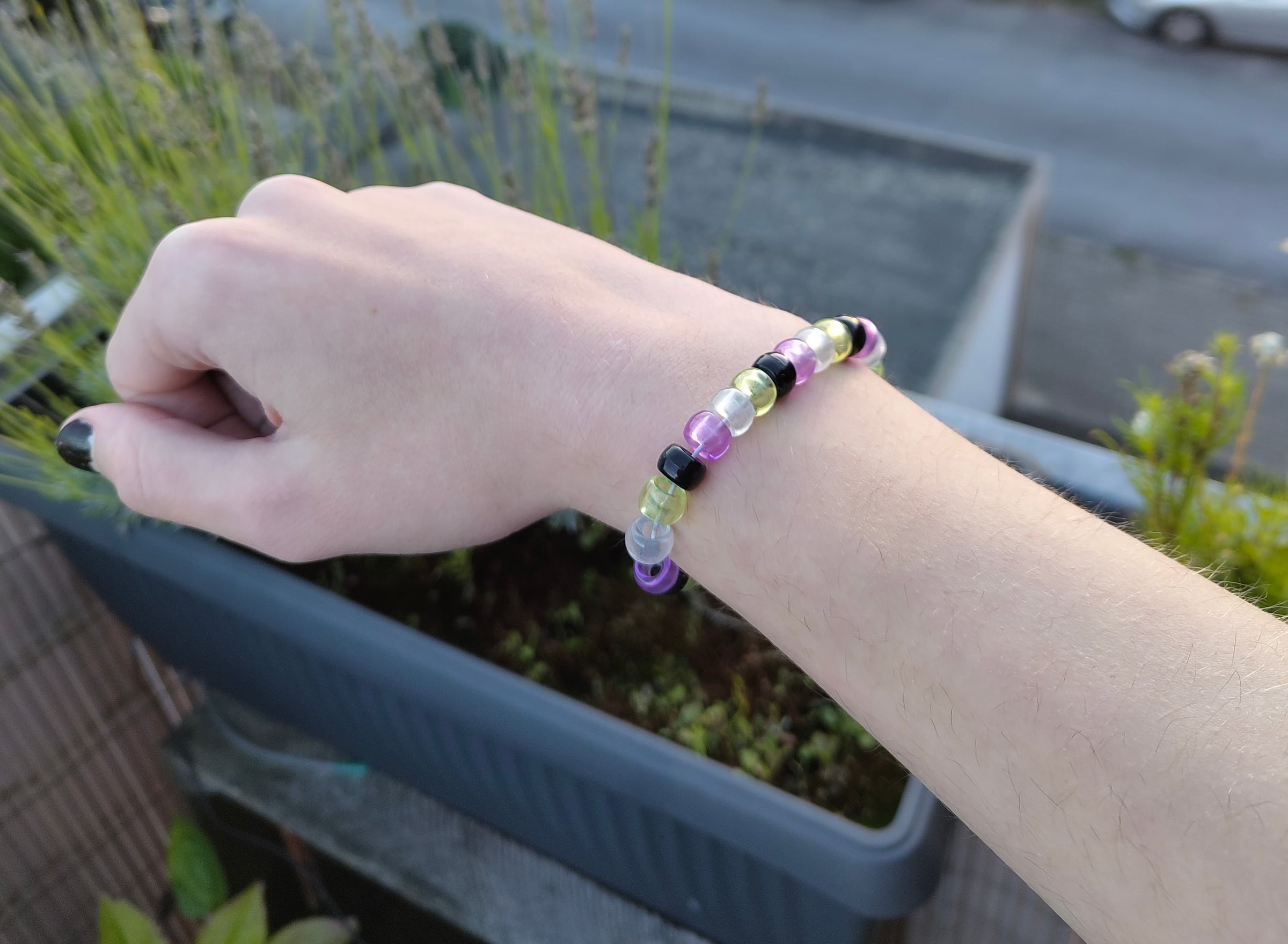 Ein Armbändchen in den Farben der Nonbinary-Flagge, an meinem rechten Arm.